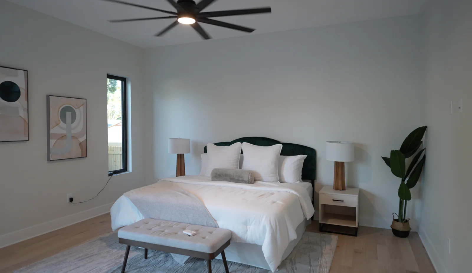 Bedroom with a green headboard, white bedding, upholstered bench, and ceiling fan